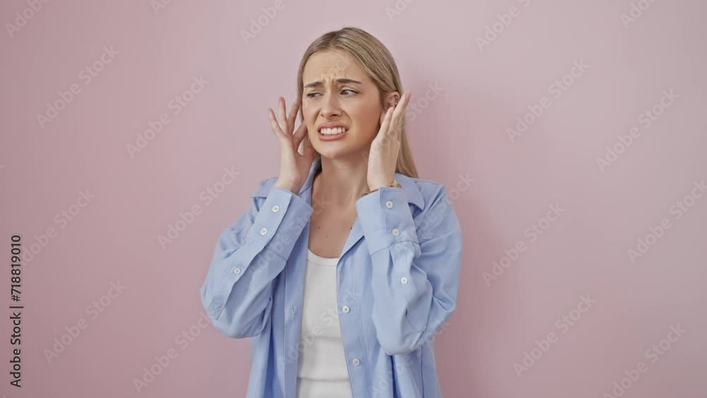 Fed up and over it, young blonde woman, stressed by loud noise, wearing pink shirt, covering ears with fingers in annoyance over isolated background Fed up and over it, young blonde woman, stressed by loud noise, wearing pink shirt, covering ears with fingers in annoyance over isolated background
