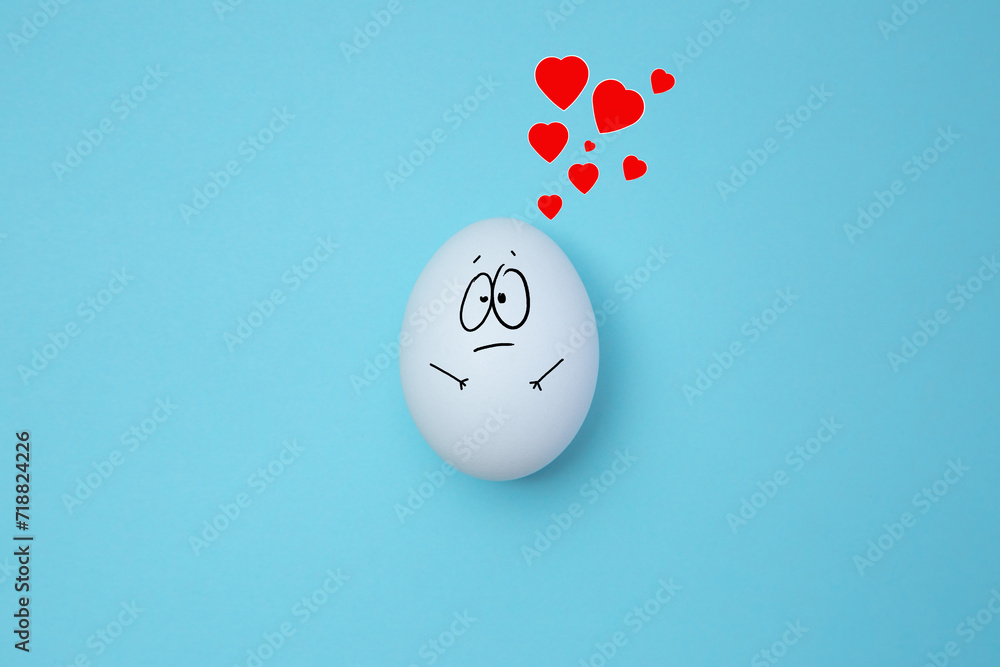 Funny white egg with face feeling on blue background with red hearts