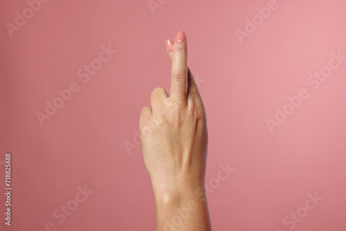 Woman crossing her fingers on pink background  closeup