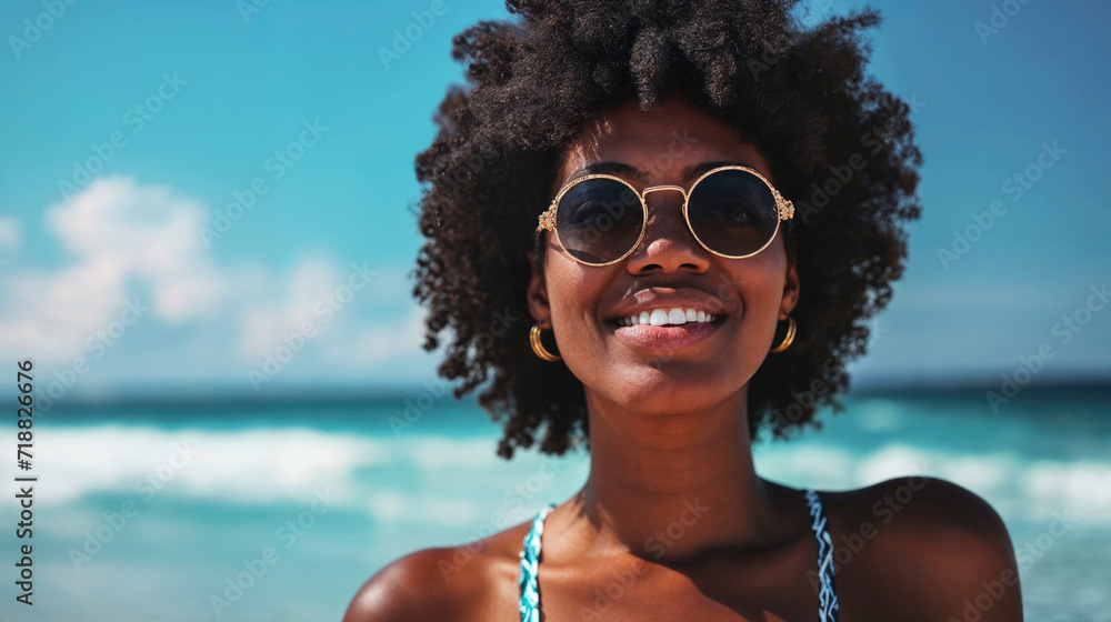 Cheerful African American woman with sunglasses enjoying a sunny day on the beach.