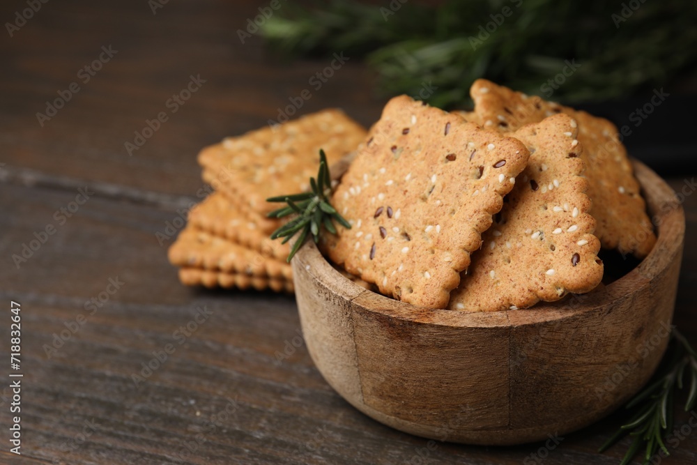 Cereal crackers with flax, sesame seeds and rosemary in bowl on wooden table, closeup. Space for text Cereal crackers with flax, sesame seeds and rosemary in bowl on wooden table, closeup. Space for text