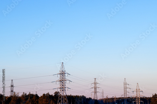 Electric line masts in a wooded area against a blue sky background