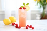 pink lemonade in a clear glass, garnished with raspberries