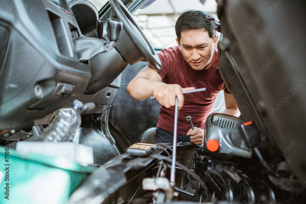 a male mechanic checks the engine under the car seat at a repair shop a male mechanic checks the engine under the car seat at a repair shop