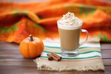 pumpkin spice latte with a dollop of whipped cream, on a burlap mat