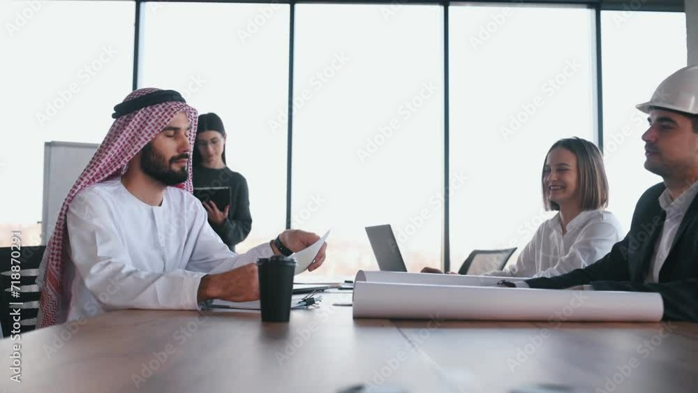 Side view. Muslim businessman in traditional outfit with colleagues in office.