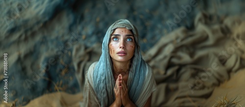 Biblical character. Emotional close up portrait of a woman with blue eyes in a veil looking up and praying. photo