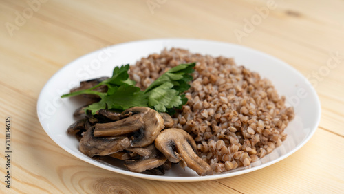 Buckwheat porridge with boiled mushrooms, willow herbs on wooden background