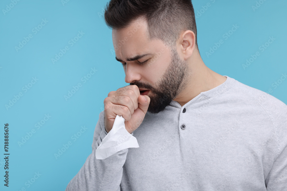 Sick man with tissue coughing on light blue background, space for text Sick man with tissue coughing on light blue background, space for text