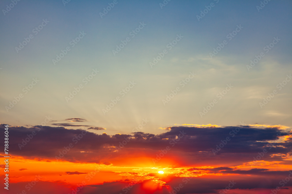 Sunset sky background with clouds and sun rays. Beautiful nature scene in the evening