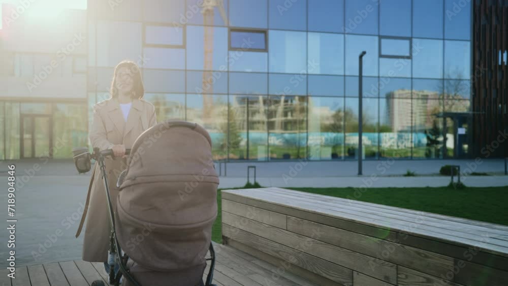 Attractive Mom Wearing Brown Trench Coat, Walking in Sunny Park with Stroller Near Local Lake. Attractive Mom Wearing Brown Trench Coat, Walking in Sunny Park with Stroller Near Local Lake.