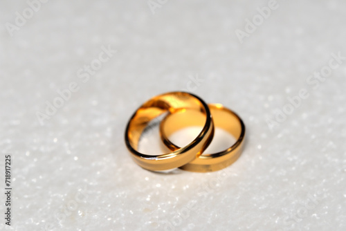 wedding rings. two golden wedding rings lie on a white shiny table, viewed from afar, wedding concept