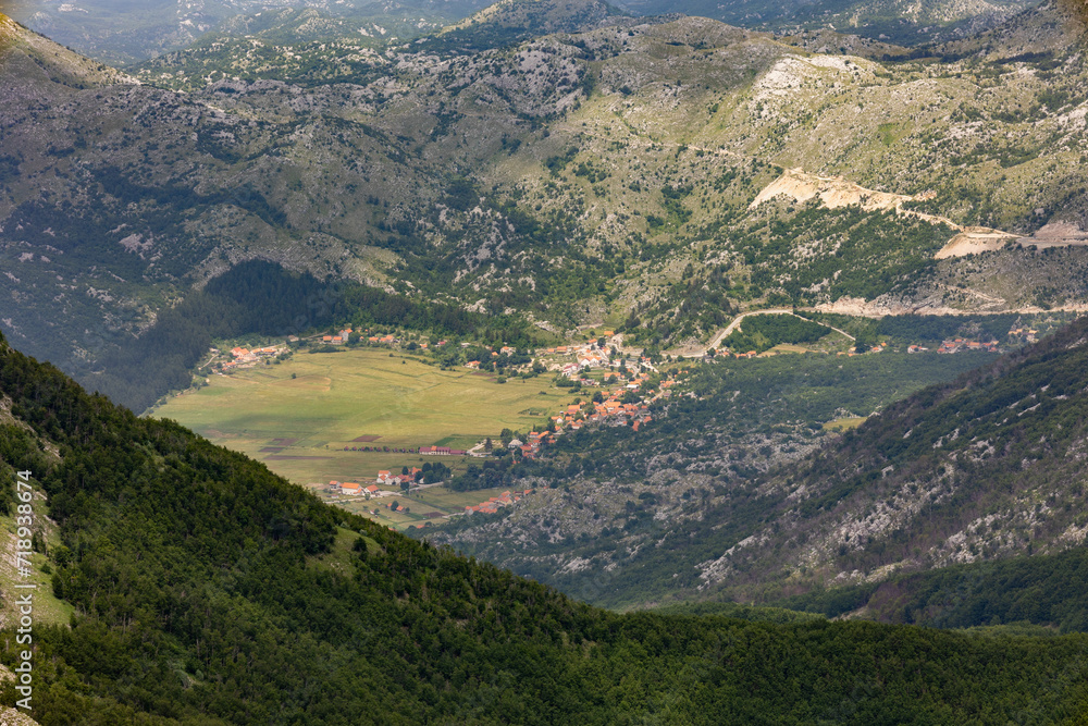 Aerial shot from the Mausoleum of Njegoš for a small town in Lovcen, Montenegro. Houses cluttered together surrounded by lush green mountains Aerial shot from the Mausoleum of Njegoš for a small town in Lovcen, Montenegro. Houses cluttered together surrounded by lush green mountains