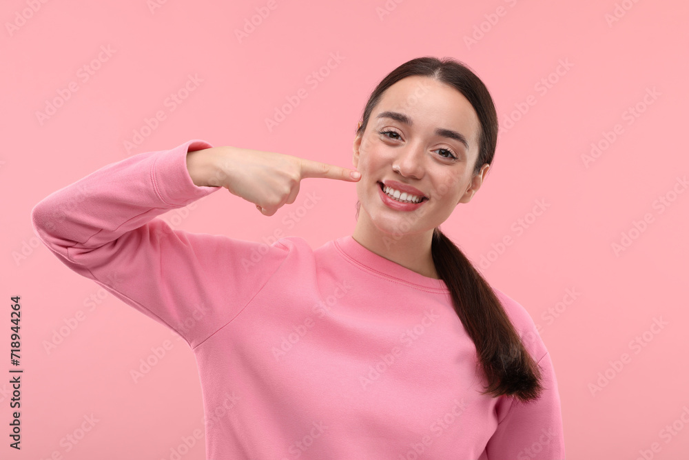 Beautiful woman showing her clean teeth and smiling on pink background Beautiful woman showing her clean teeth and smiling on pink background