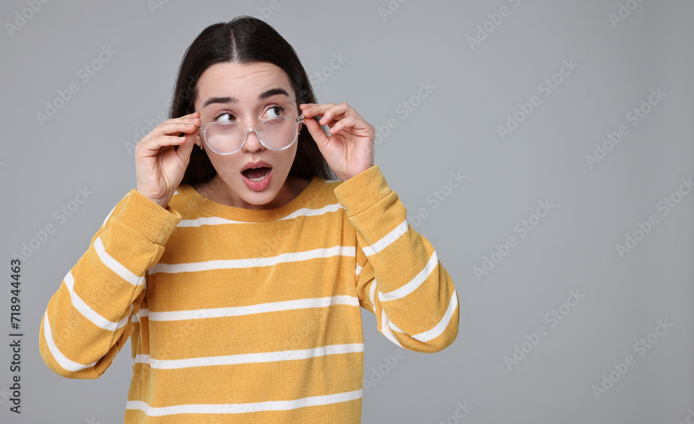Portrait of surprised woman on grey background. Space for text