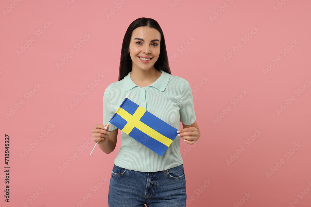 Happy young woman with flag of Sweden on pink background Happy young woman with flag of Sweden on pink background
