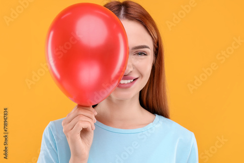 Happy woman with red balloon on orange background © New Africa