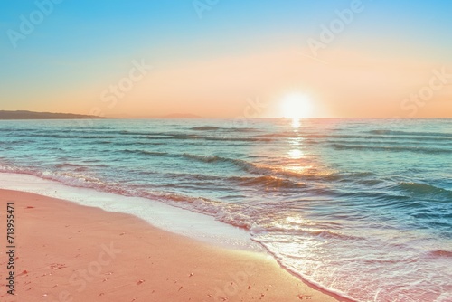 Colorful sunset viewed from the pink sea beach with soft waves photo