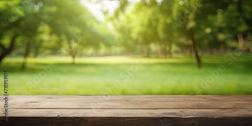 Blurred green nature in park serves as background for empty wooden table.