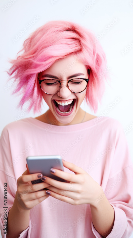 A pink-haired young woman looking at the smartphone and laughing closeup. A pink-haired young woman looking at the smartphone and laughing closeup.