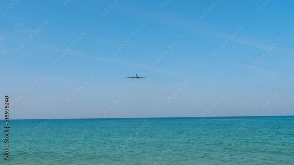 Civil plane approaching to land over the azure sea, bottom view. Airliner arrival on the island. Tourism and travel concept Civil plane approaching to land over the azure sea, bottom view. Airliner arrival on the island. Tourism and travel concept