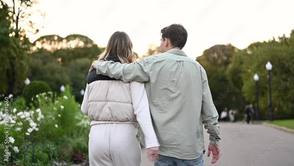 A young couple walks cutely through the park, view from the back, close-up. A young couple walks cutely through the park, view from the back, close-up.
