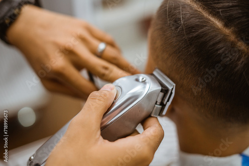 barber's hand shaving customer hair with electric shaver cropped side view