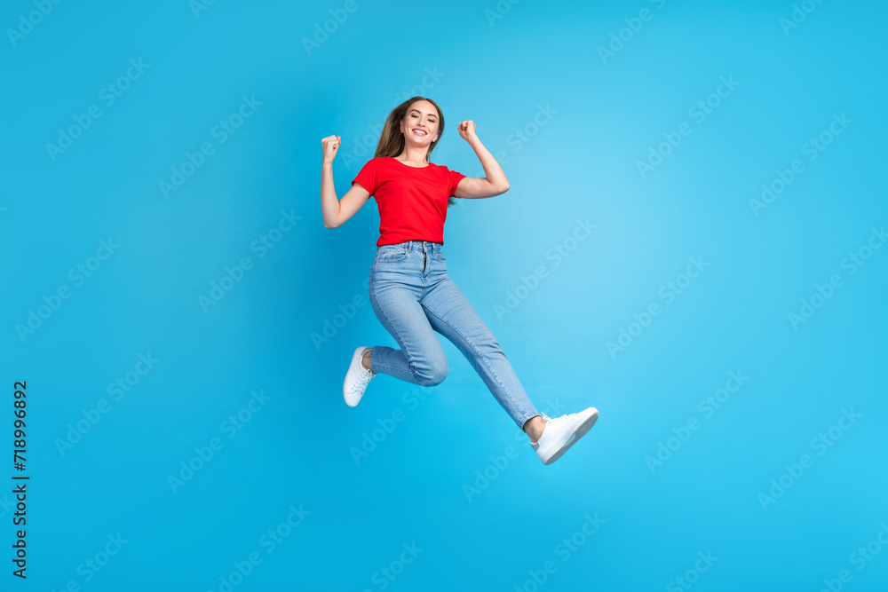 Photo of overjoyed cheerful girl dressed stylish clothes raised fists summer seasonal sale isolated on blue color background Photo of overjoyed cheerful girl dressed stylish clothes raised fists summer seasonal sale isolated on blue color background