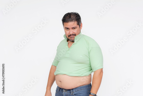 фотографія An overweight man looks annoyed after his old shirt barely fits, his belly sticking out