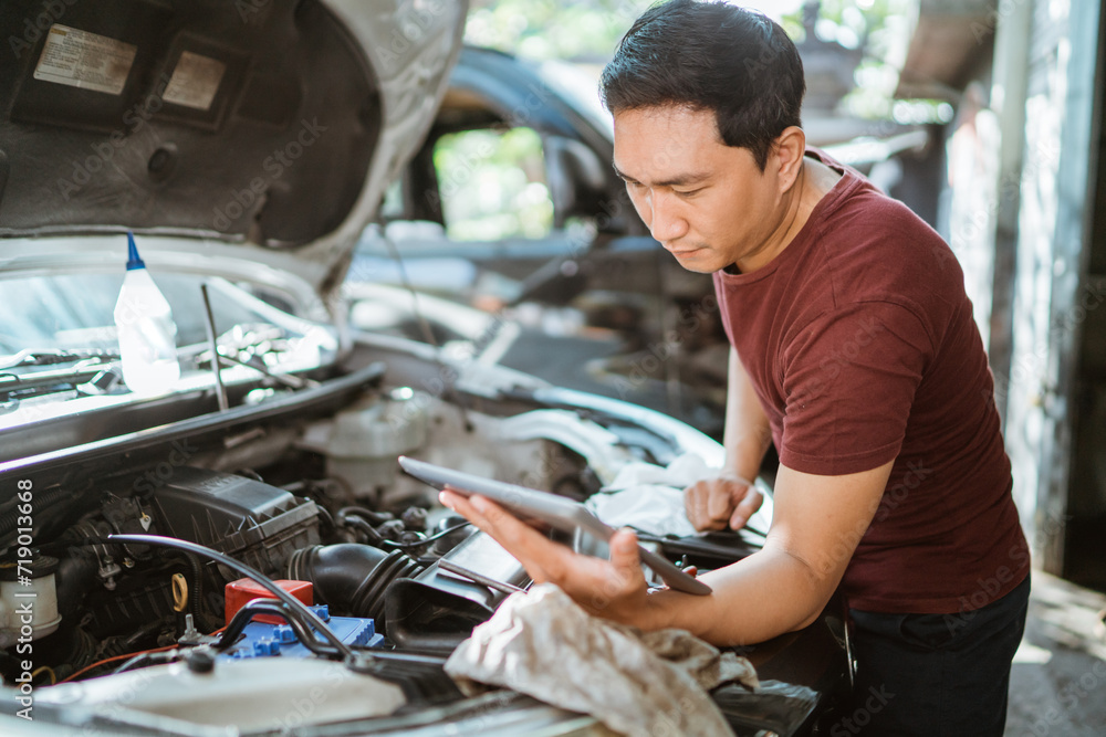 car mechanic using a tablet digital to diagnosing on car engines parts for repair at workshop car mechanic using a tablet digital to diagnosing on car engines parts for repair at workshop