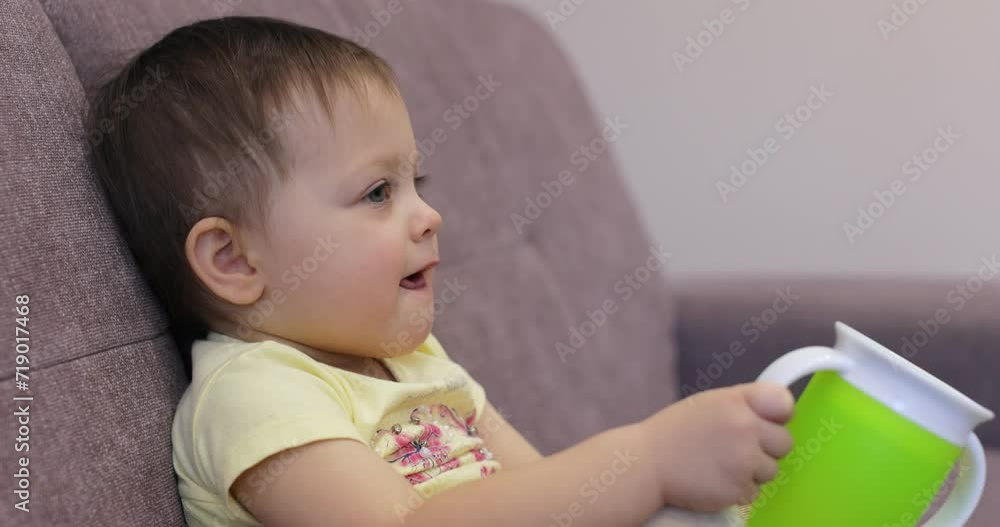 little baby child with water bottle watching tv sitting on coach at home little baby child with water bottle watching tv sitting on coach at home