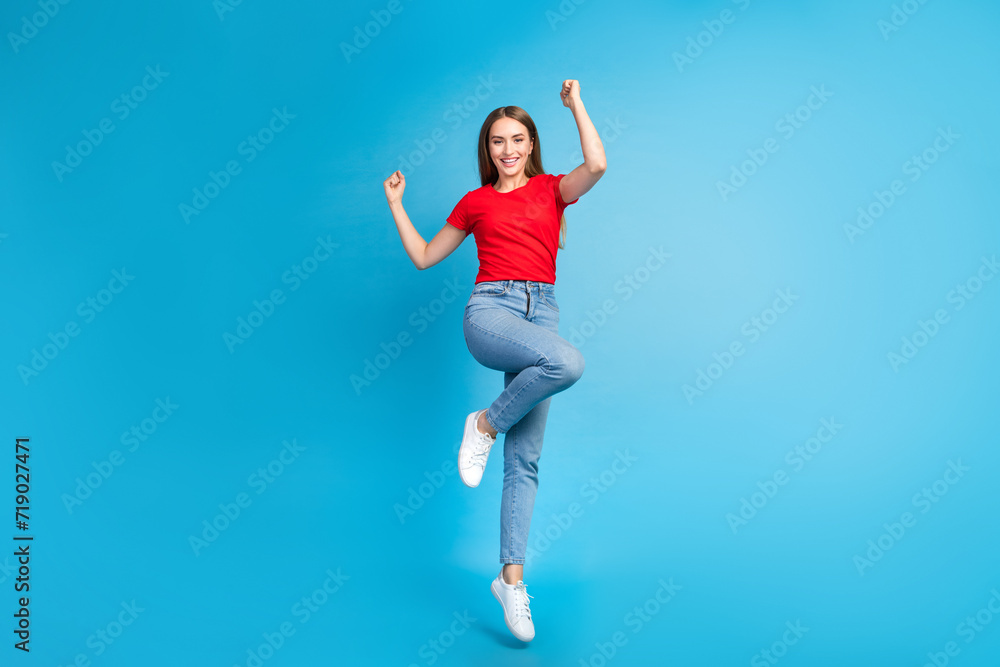 Obraz premium Full length photo of positive glad girl dressed stylish clothes raise hands yes good news isolated on blue color background
