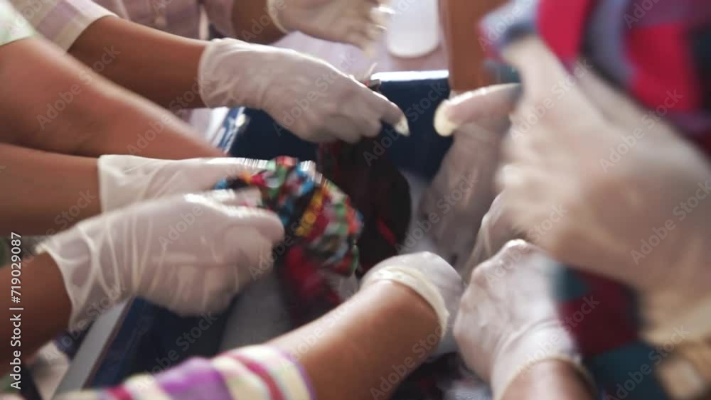 The hands of several people wearing rubber gloves were washing laundry mixed with detergent. The hands of several people wearing rubber gloves were washing laundry mixed with detergent.