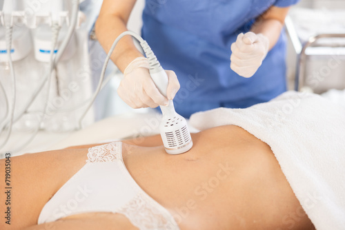 Φωτογραφία Cosmetologist performing cryotherapy using cooling attachment to tighten skin on female client belly in cosmetology clinic