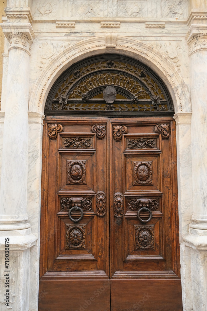 Beautiful carved wooden door across marble wall close-up. Building exterior, facade