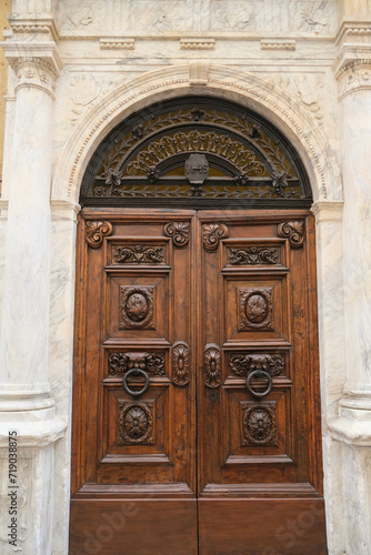 Beautiful carved wooden door across marble wall close-up. Building exterior, facade