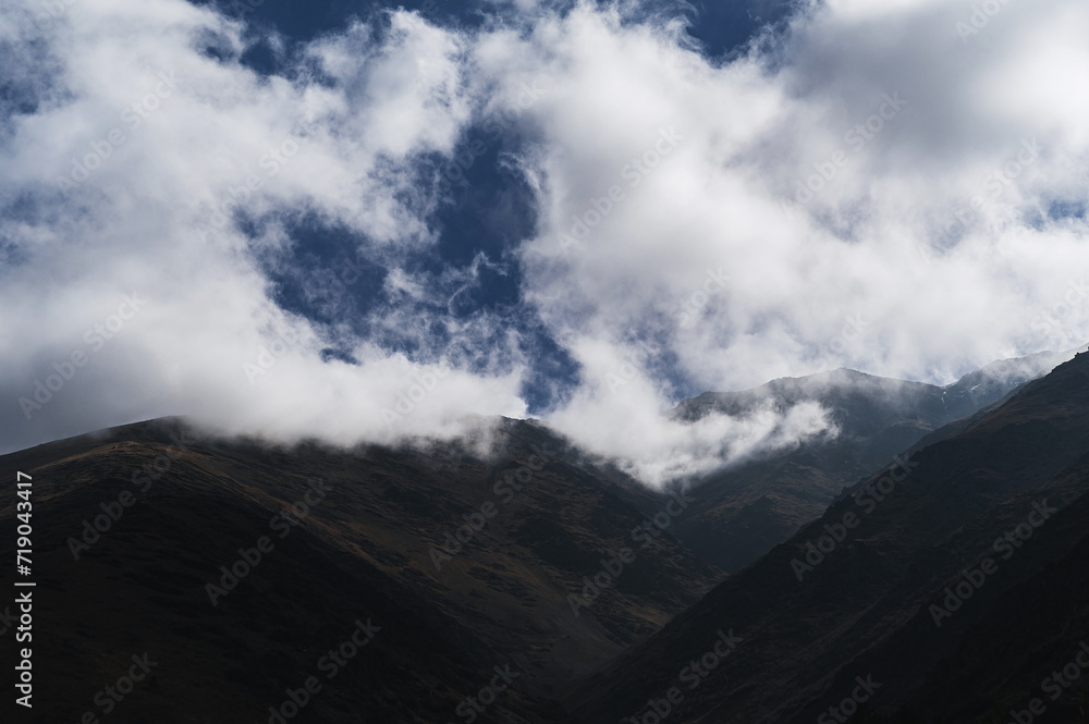 mountain peaks in fog against the sky with clouds in autumn