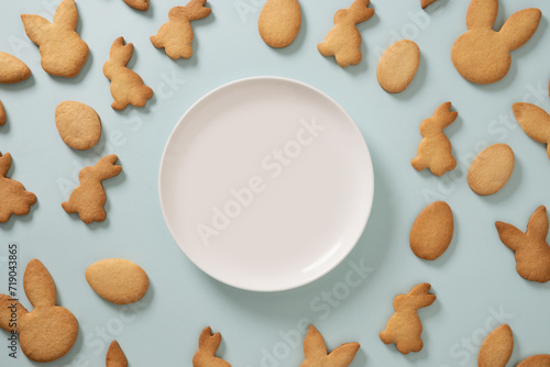 Easter cookies shaped of bunny on blue background. View from above. Festive food and kids snacks. Holiday Easter pattern.