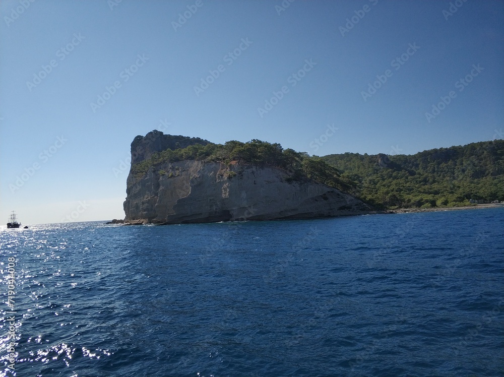 Blue sea and rocks, a ship is sailing on the horizon Blue sea and rocks, a ship is sailing on the horizon
