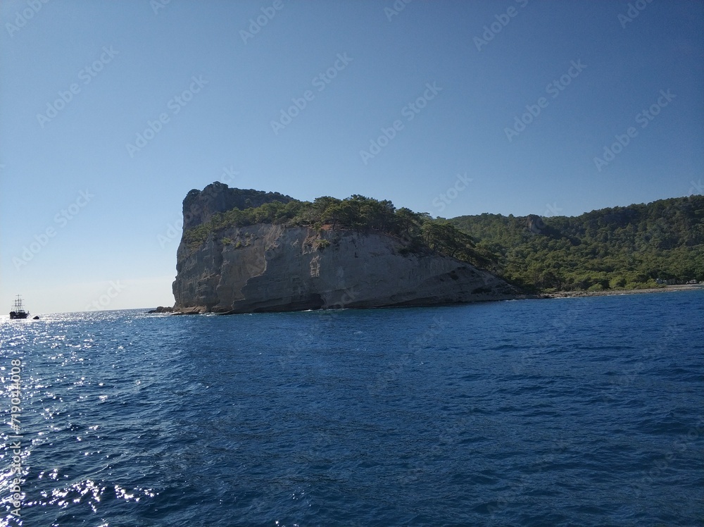 Blue sea and rocks, a ship is sailing on the horizon