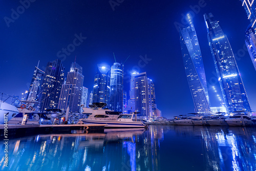 Photography Night photo of Dubai Marina with white yacht and neon color illuminated of skyscrapers