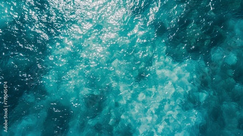 A serene ocean reflecting the vibrant hues of aqua and teal, its fluid surface rippling in a mesmerizing dance, inviting us to dive into the underwater world