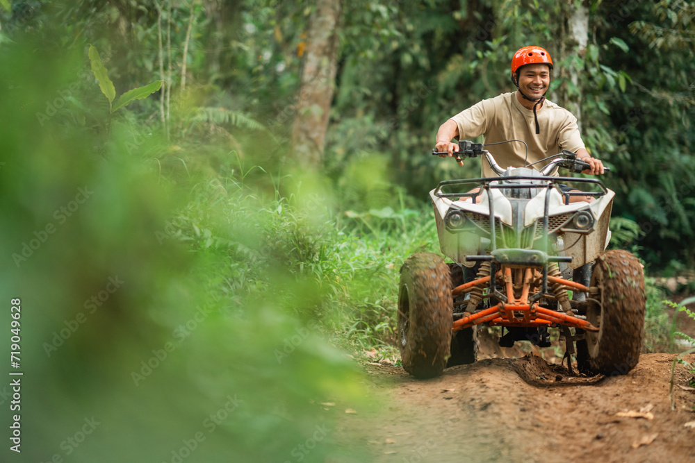 Fototapeta premium asian man smiling brightly while riding the atv to spend holidays