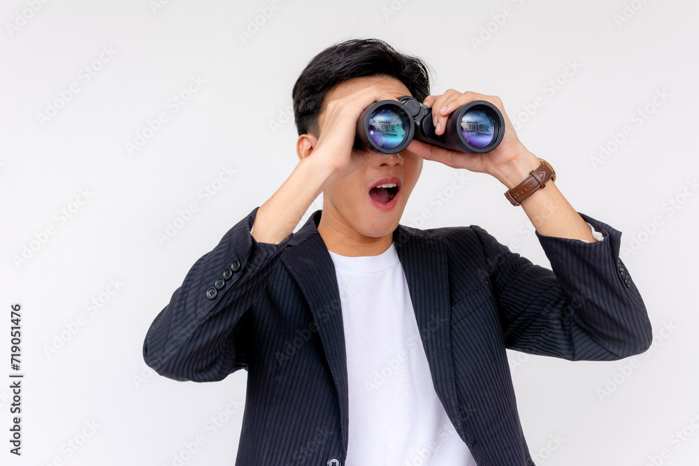 A cheerful young Asian man with a surprised expression while using the binoculars, isolated on a white background. A cheerful young Asian man with a surprised expression while using the binoculars, isolated on a white background.