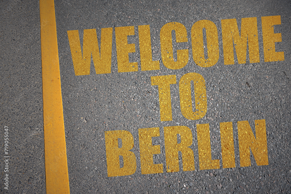asphalt road with text welcome to Berlin near yellow line.