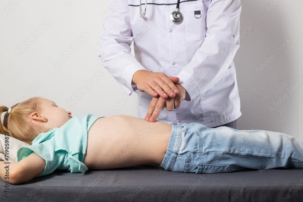 A doctor surgeon examines and diagnoses the abdomen of a seven-year-old little girl who has abdominal pain. Concept of appendicitis in children, nausea and discomfort. Copy space for text