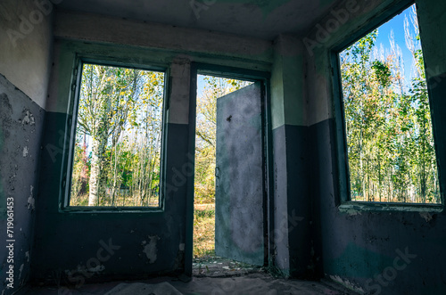 view of the forest from a room with windows and a door of an old abandoned house in Ukraine