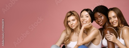 Multi Ethnic Group of Womans with diffrent types of skin sitting together and looking on camera. Diverse ethnicity women - Caucasian, African and Asian against pink background