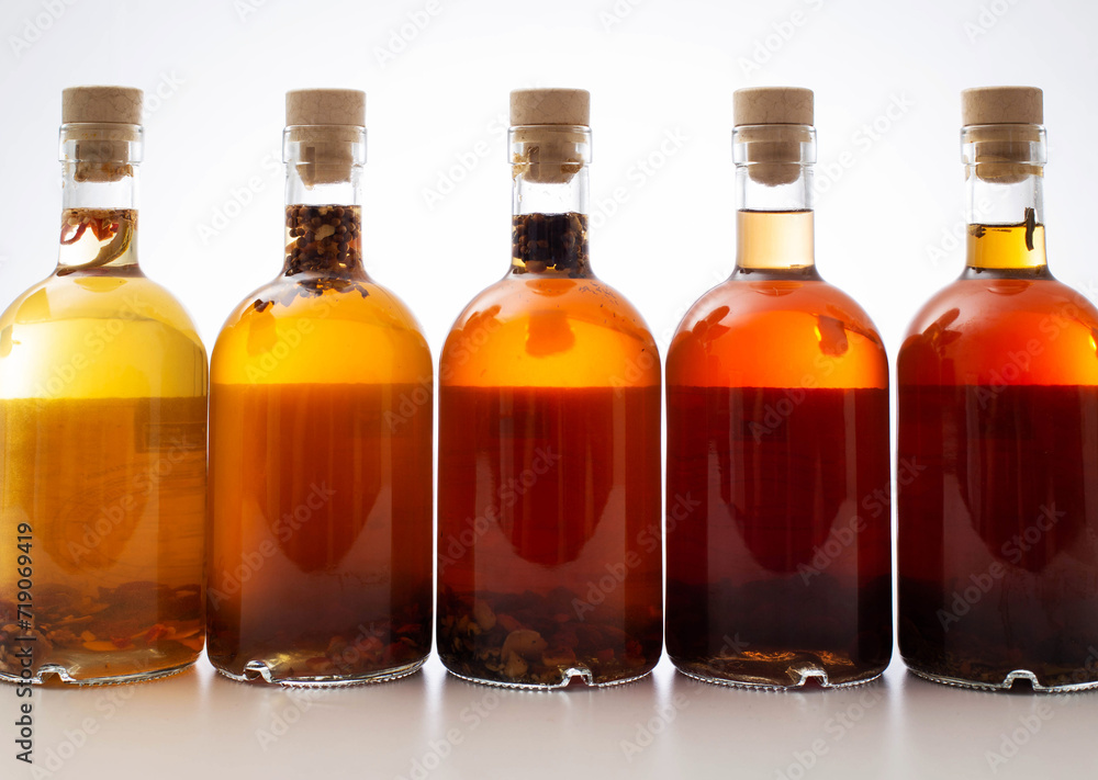 Bottles with transparent brown alcoholic drink on a white background. Homemade herbal tincture of herbal moonshine. Elite alcohol.