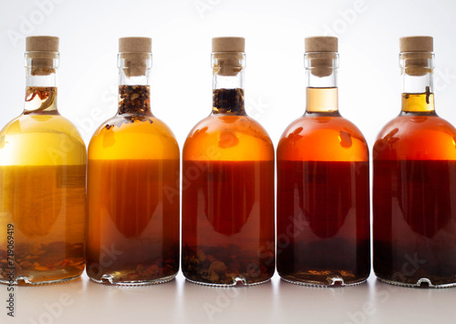 Bottles with transparent brown alcoholic drink on a white background. Homemade herbal tincture of herbal moonshine. Elite alcohol.